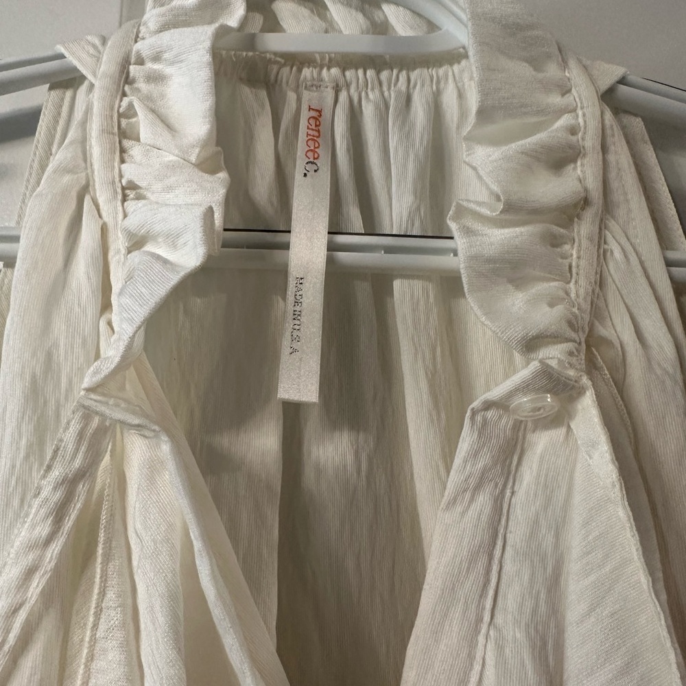 Renee C white asymmetrical hem top. Beautifully detailed with ruffle and bow.